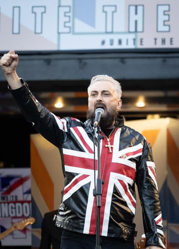 Rikki Doolan performing on stage, fist raised