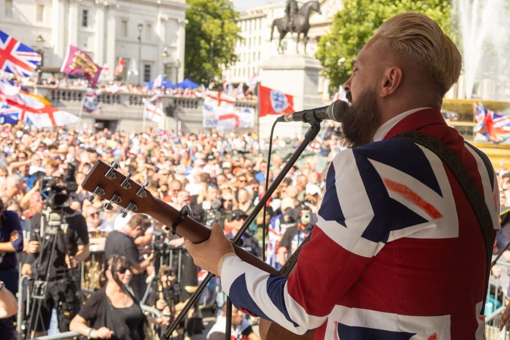 Rikki Doolan playing guitar on stage at Trafalgar Square